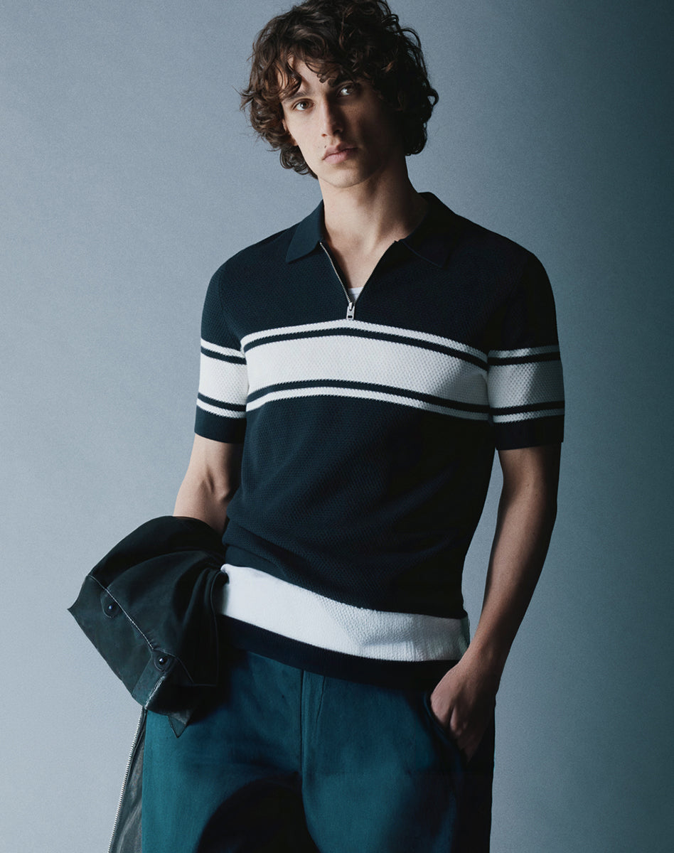 Navy knit polo with white stripes and zip collar, modern piece for a casual men’s outfit.